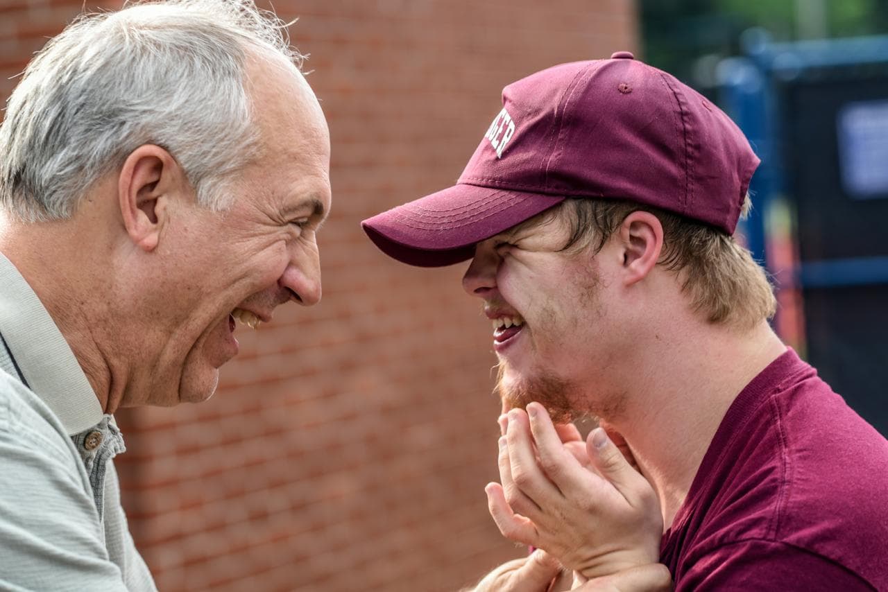 Two men laughing together outdoors.